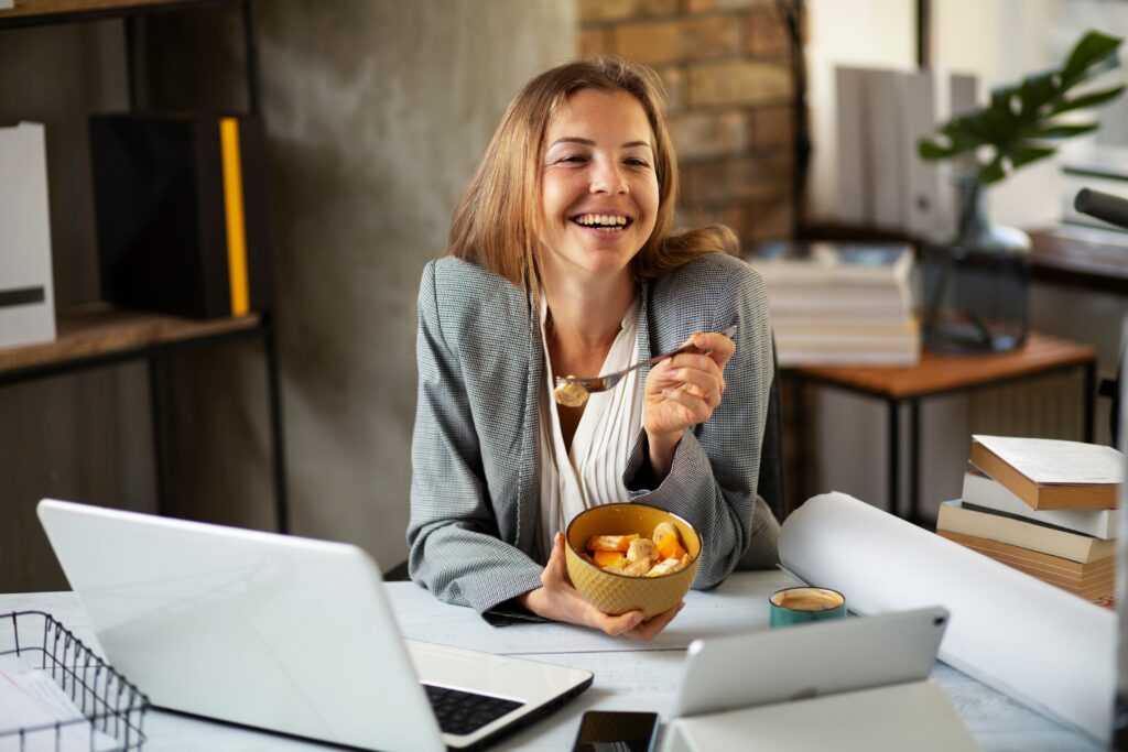 Businesswoman,In,Office,Having,Healthy,Snack.,Young,Woman,Eating,Fruit