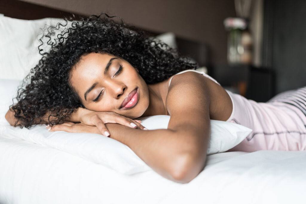 Woman,Happy,On,Bed,Smiling,And,Stretching,Looking,At,Camera